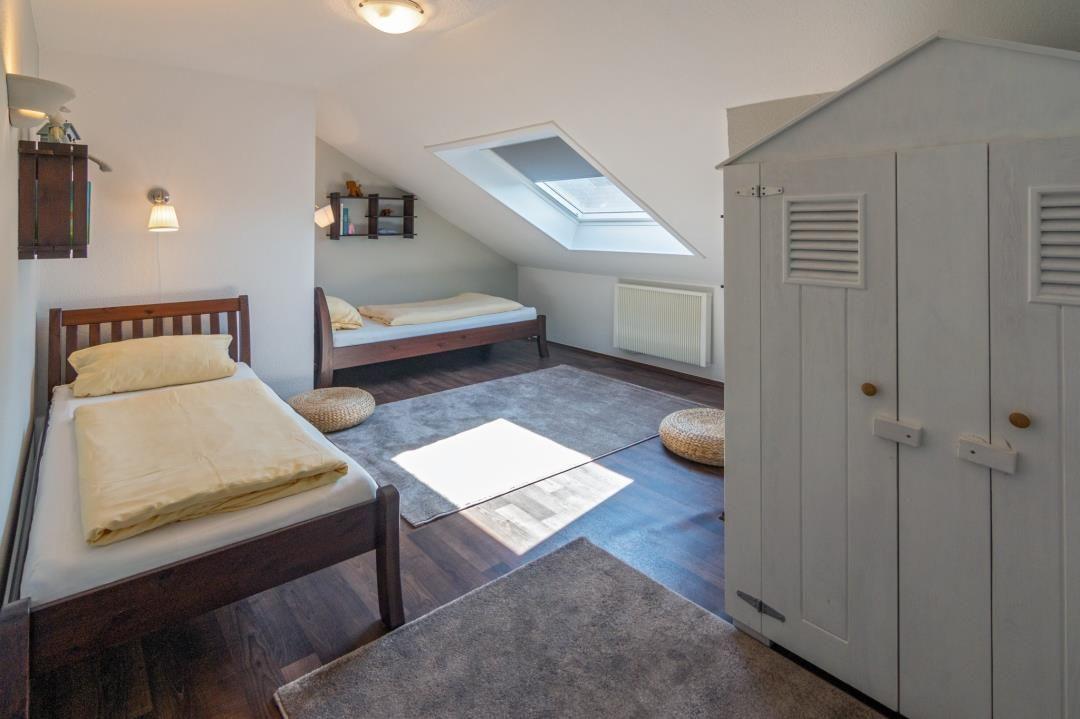 Zimmer mit zwei Betten, Dachfenster und Kleiderschrank.