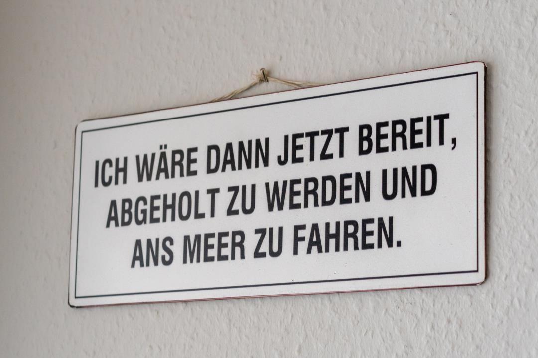 Schild an Wand: Ich wäre dann jetzt bereit, abgeholt zu werden und ans Meer zu fahren.