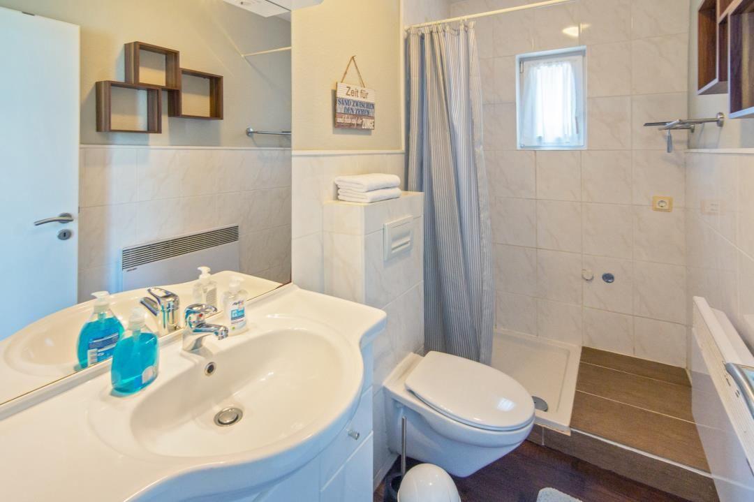 Badezimmer mit Dusche, Toilette und Waschbecken mit Spiegel.