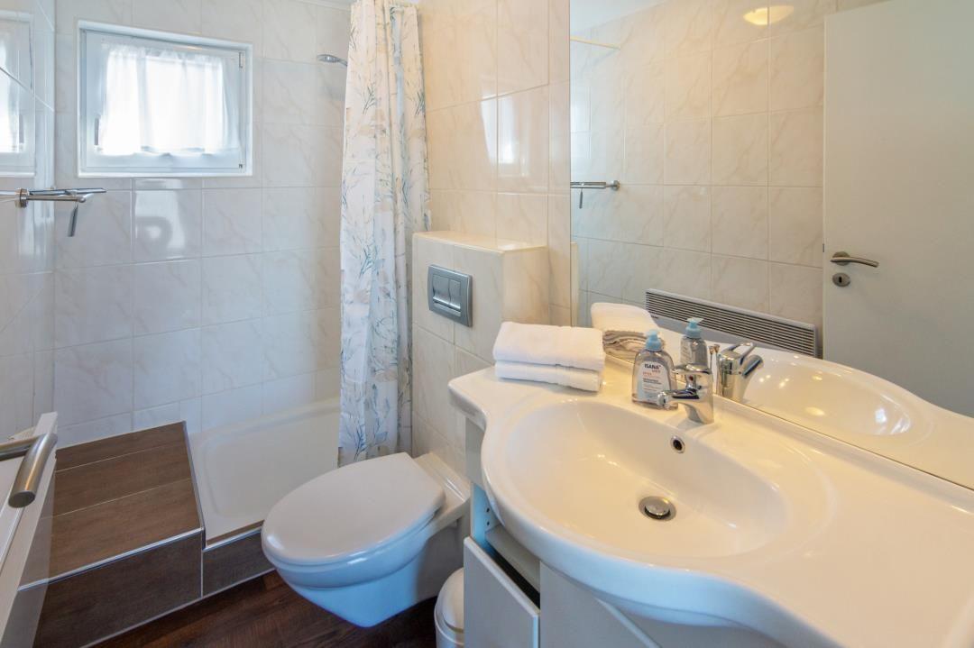 Badezimmer mit Dusche, Toilette und Waschbecken mit Spiegel.