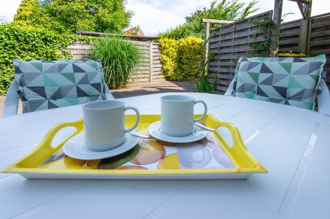 Garten-Tisch mit zwei Tassen auf einem gelben Tablett.