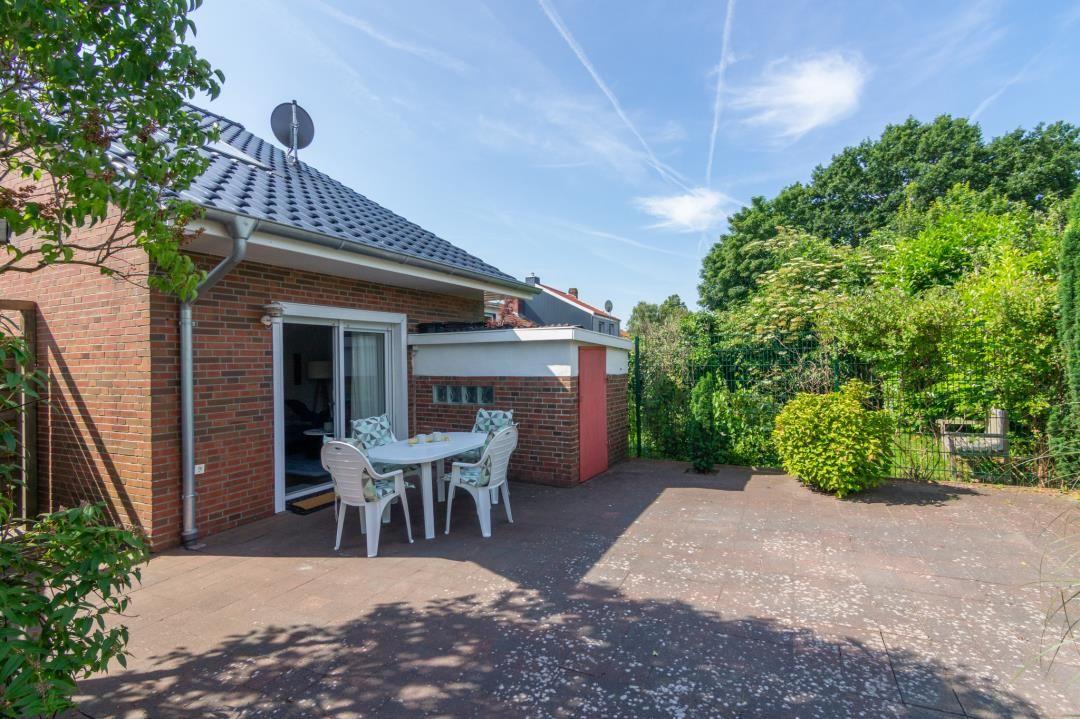 Hinterhof mit Tisch, Stühlen und Garten. Haus mit Satellitenantenne.