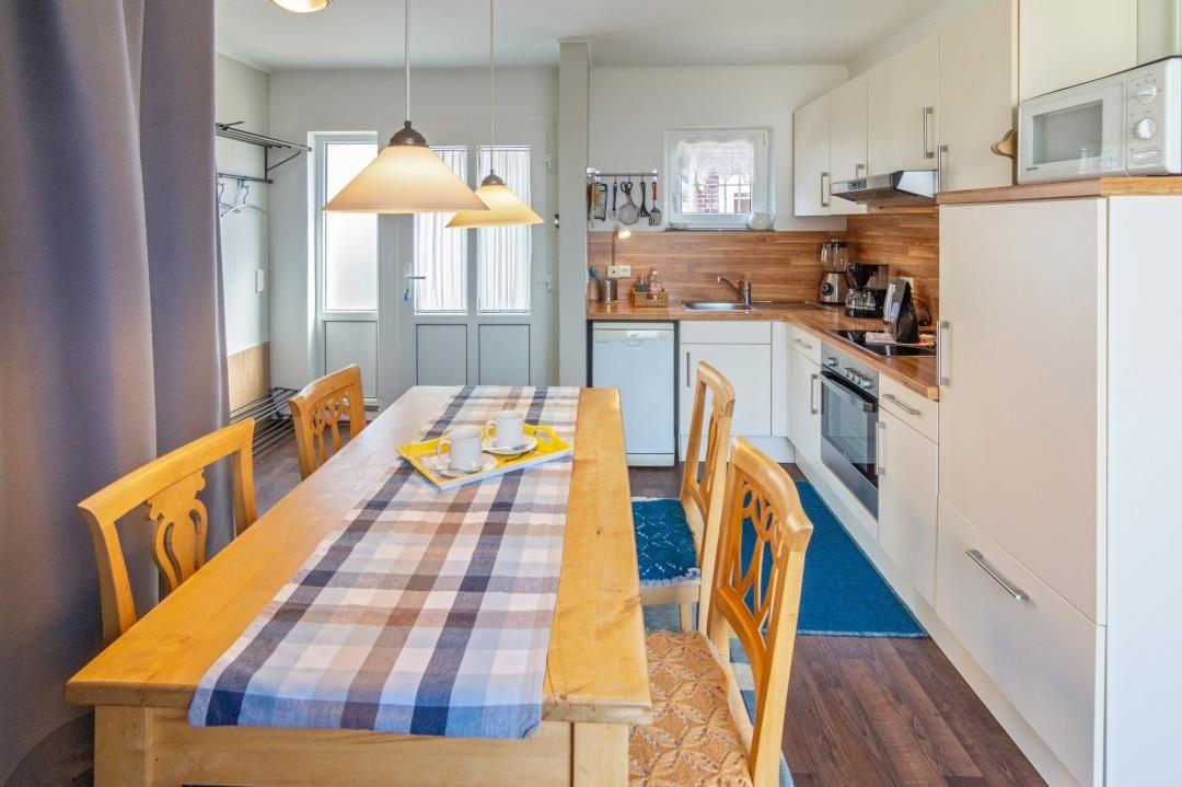 Essbereich mit Holztisch und Stühlen, Küche mit Arbeitsplatte und Geräten.