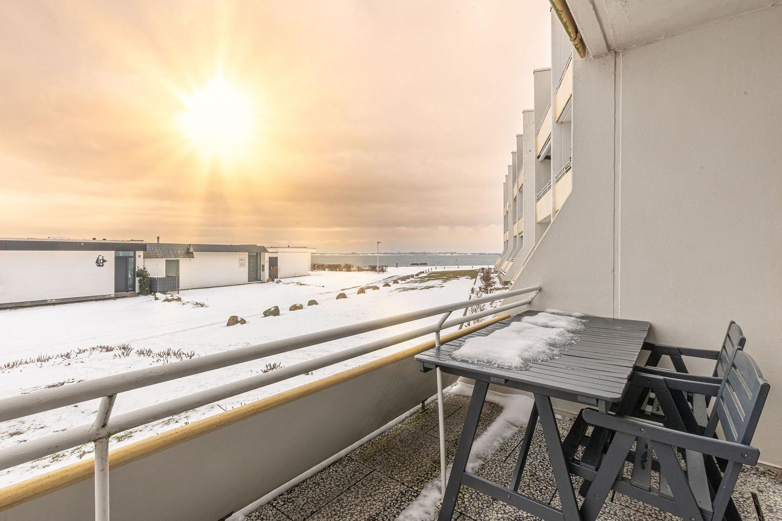 Balkon mit Tisch und Stühlen, Schnee bedeckt den Boden und die Landschaft.