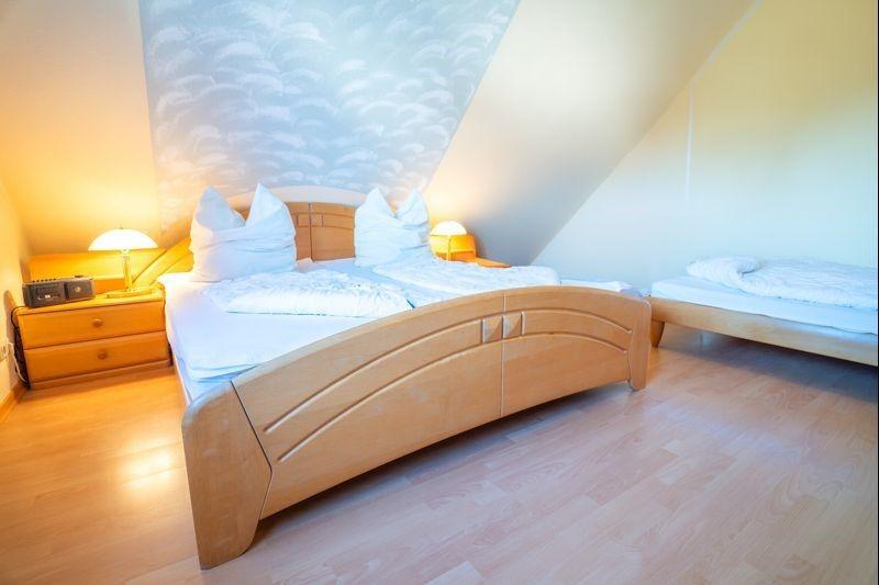 Schlafzimmer mit Doppelbett und kleinem Bett unter schrägem Dach