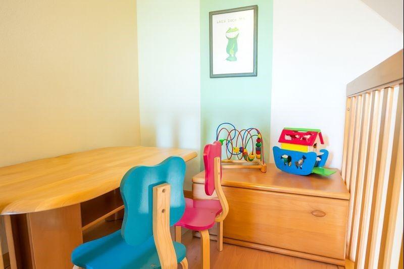 Kinderzimmer mit Holztisch, zwei Stühlen und Spielzeug auf Schrank