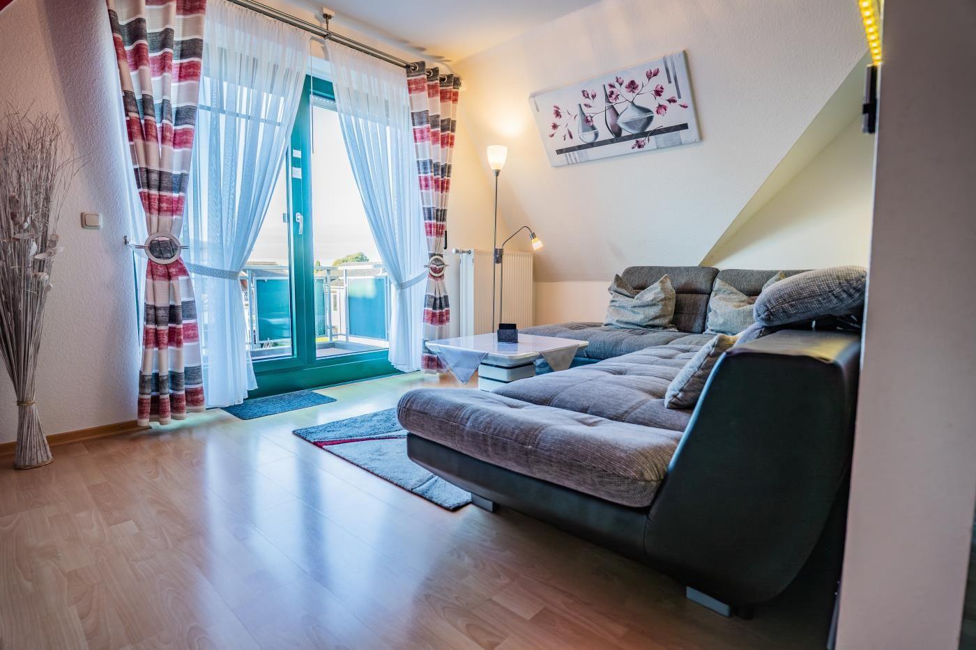 Wohnzimmer mit Sofa, Couchtisch und Balkontür mit Blick.