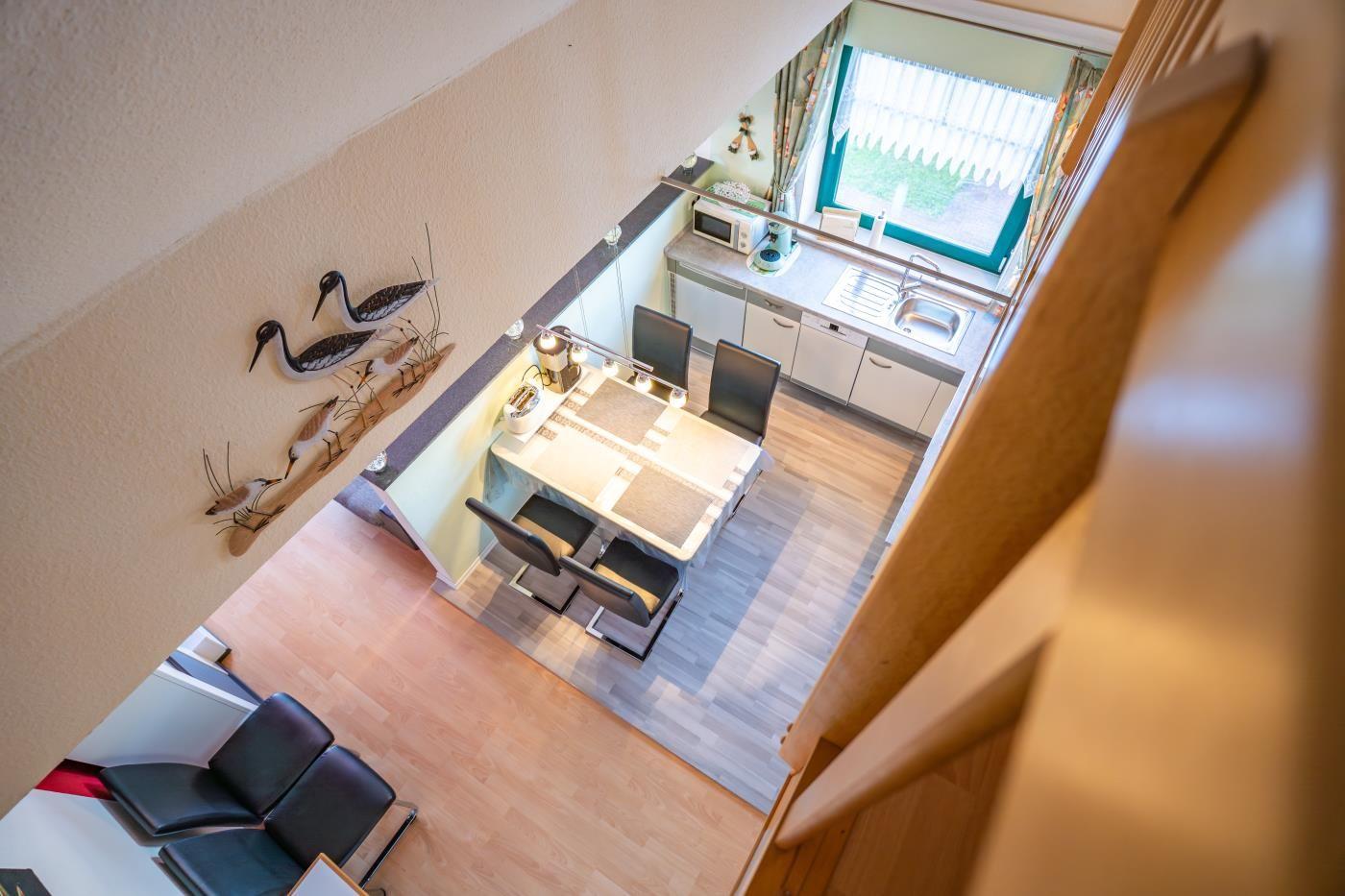 Küche und Essbereich mit Tisch, Stühlen und Fenster. Wanddekoration mit Vogelmotiven.