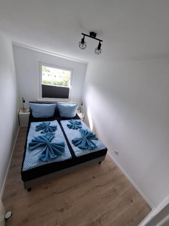 Schlafzimmer mit Doppelbett, Fenster und Holzboden. Blaue Bettwäsche und Nachttische.