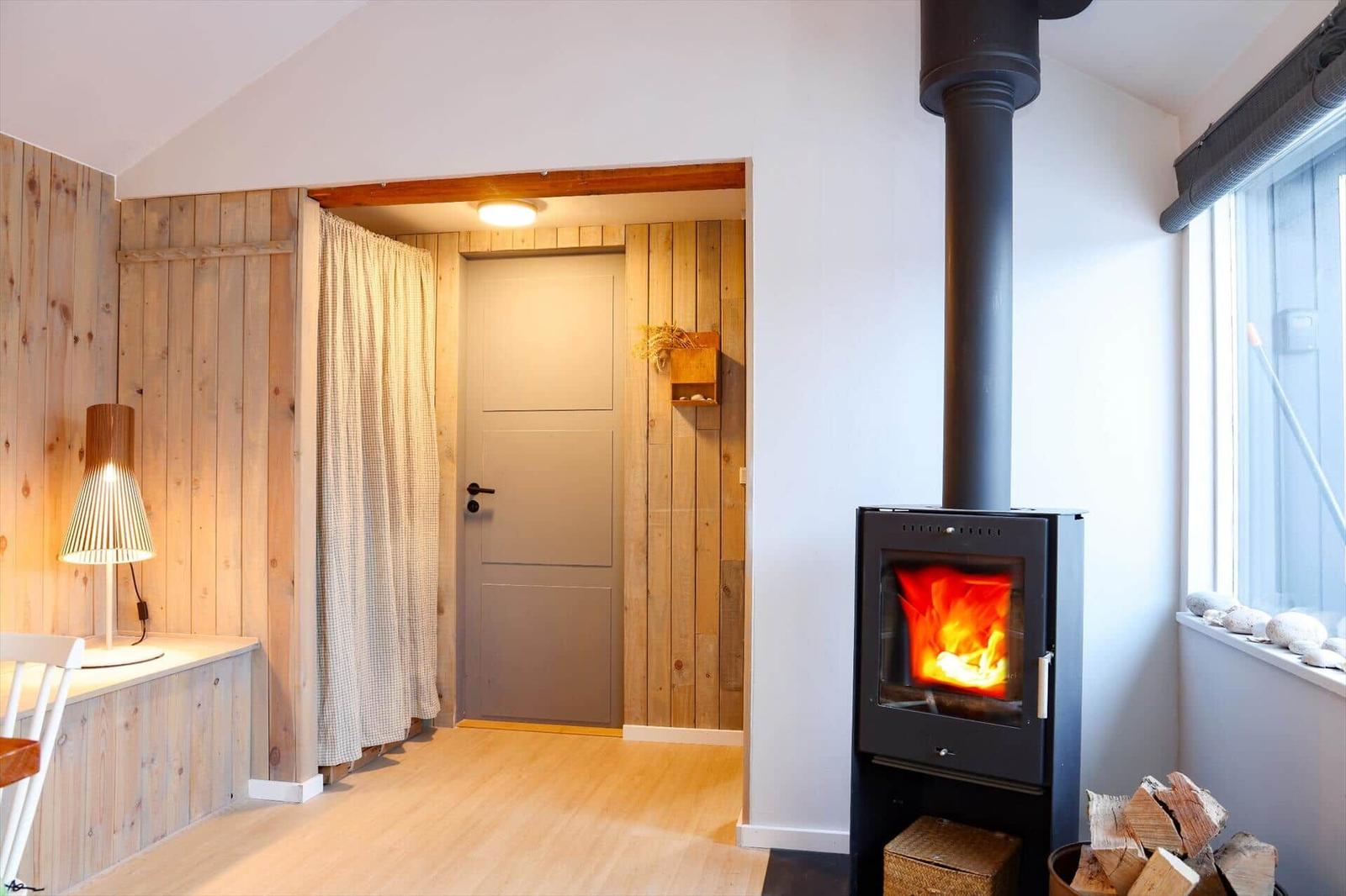 Room with fireplace, wood wall, and door with curtain.