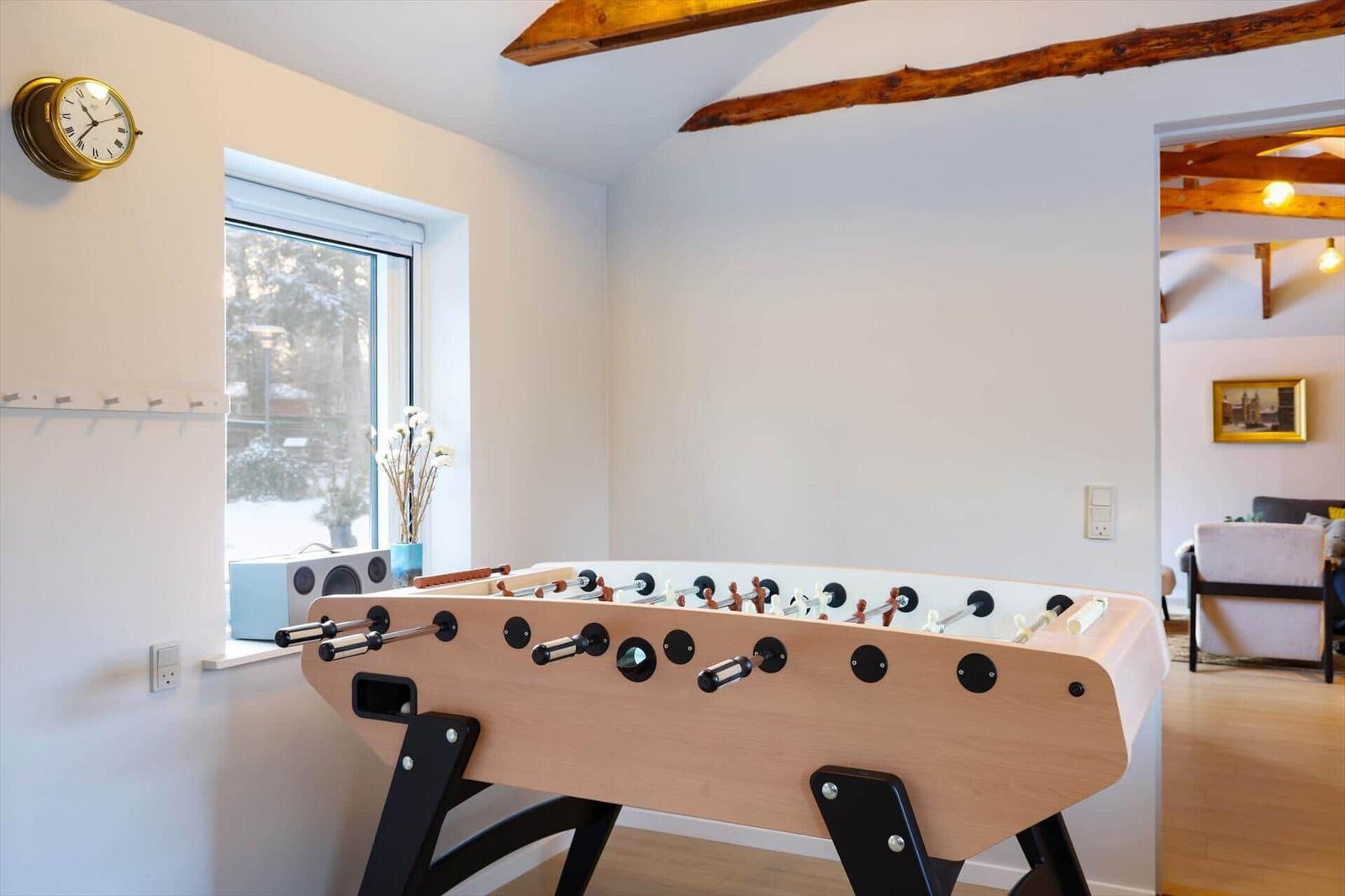 Foosball table in room with wooden beams and snowy window view.