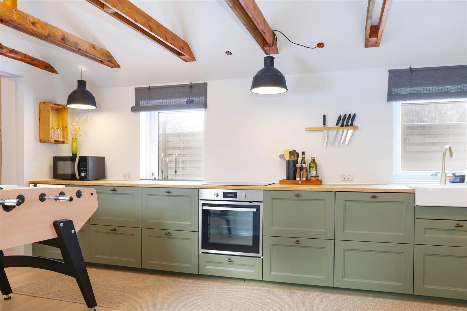 Kitchen with green cabinets, wooden countertops, and built-in oven.