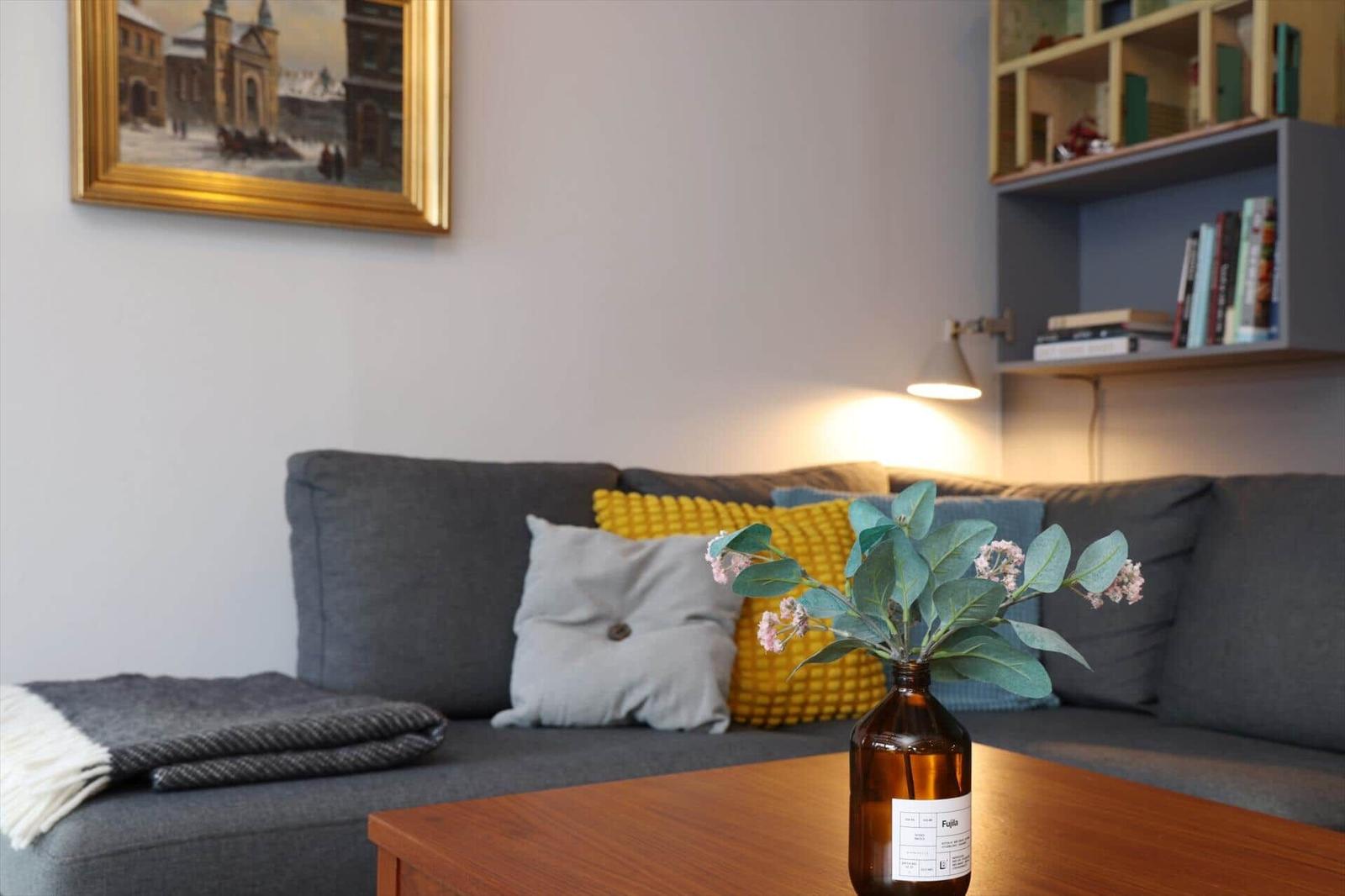 A gray sofa with cushions and a table with flowers.
