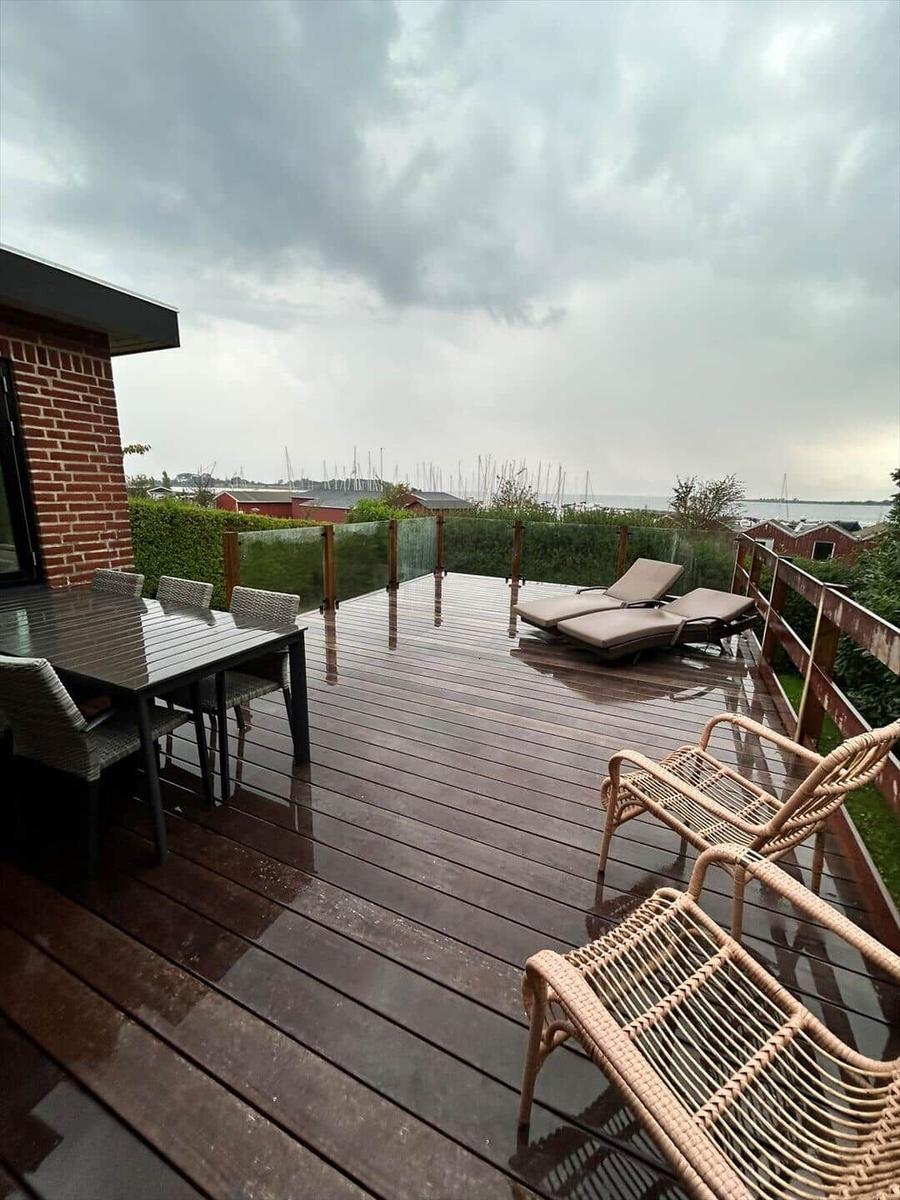 Deck with table, chairs, and loungers. View of water and boats.