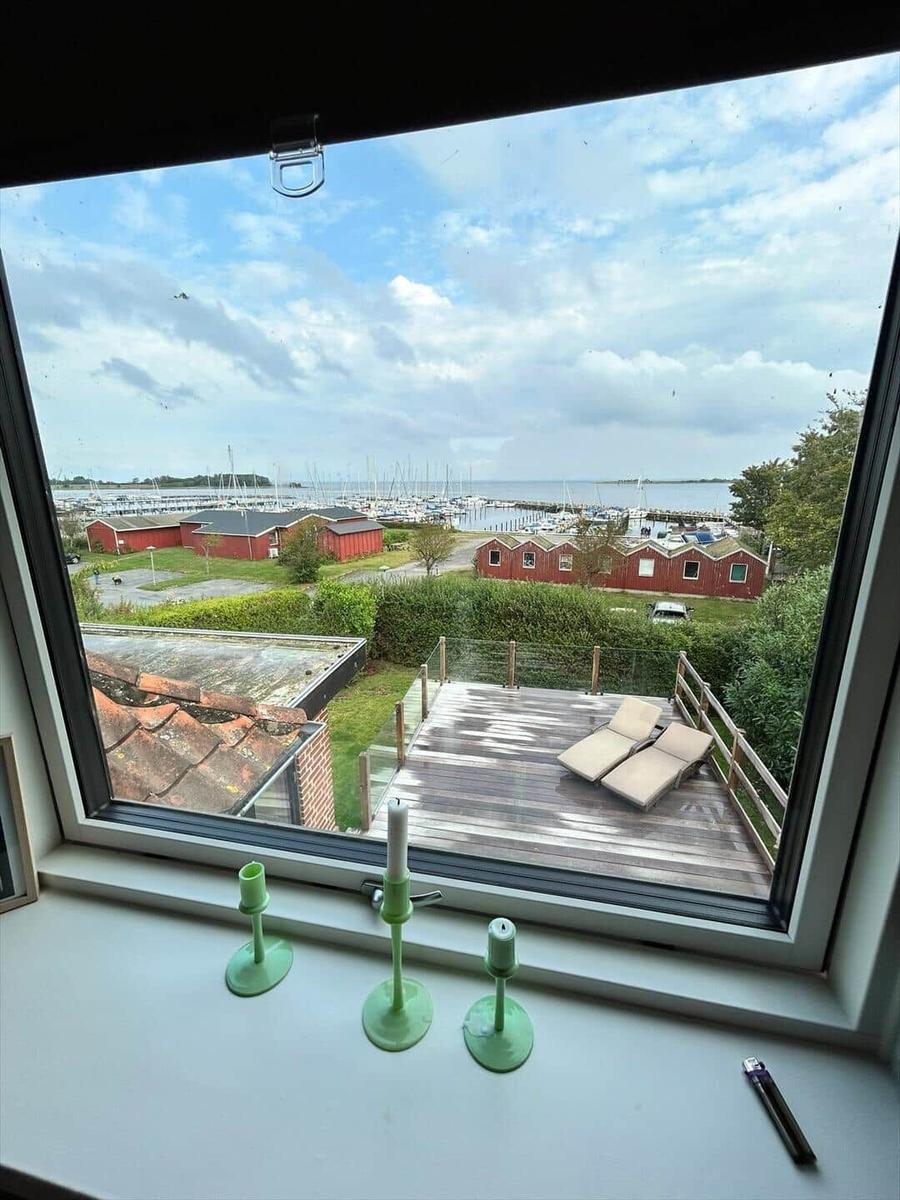 From the window, you can see a terrace with loungers and a harbor with boats.