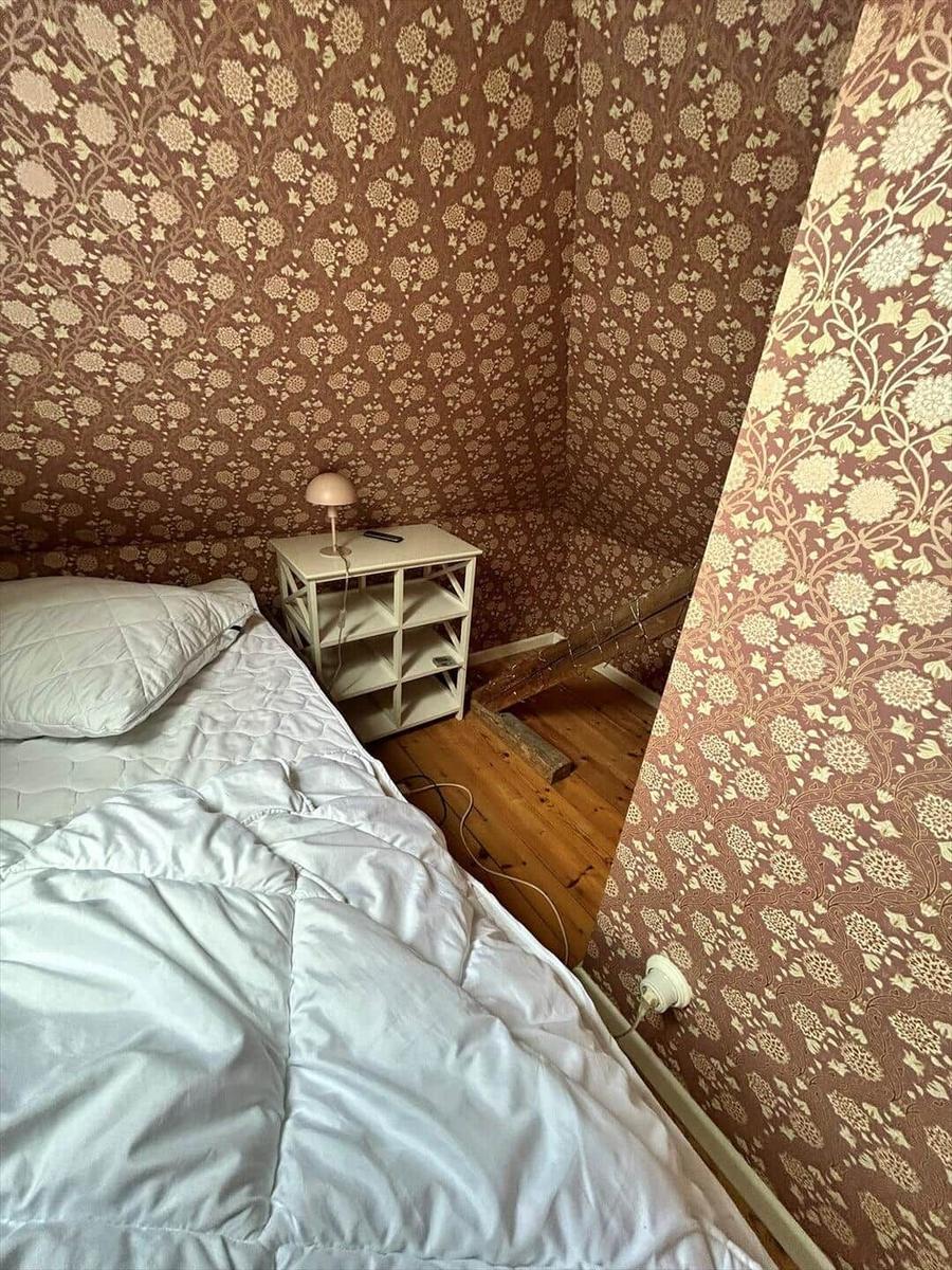 Bedroom with bed, nightstand, and floral wallpaper on the walls.