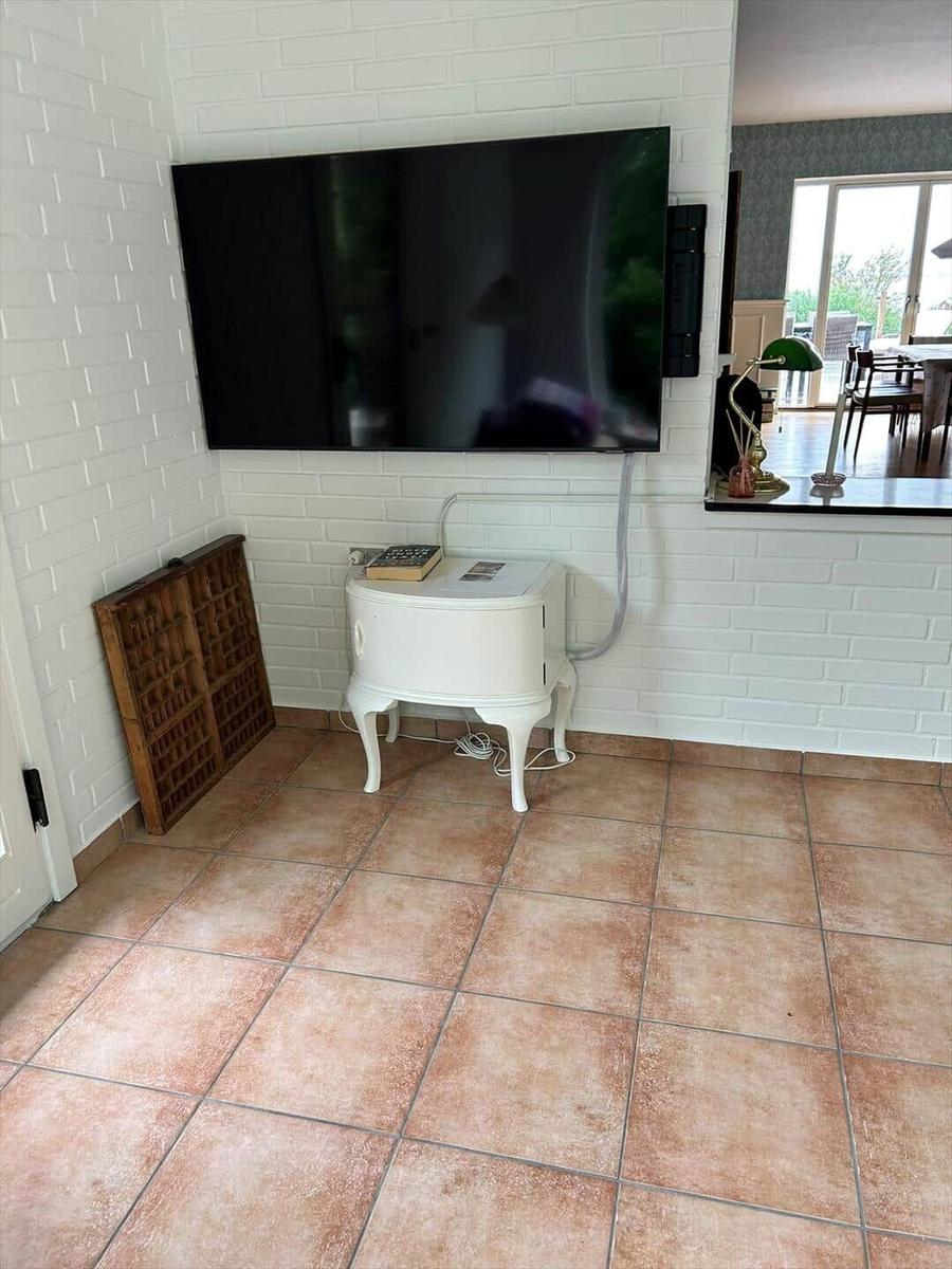Living area with TV on white brick wall, white side table, and terrace door.