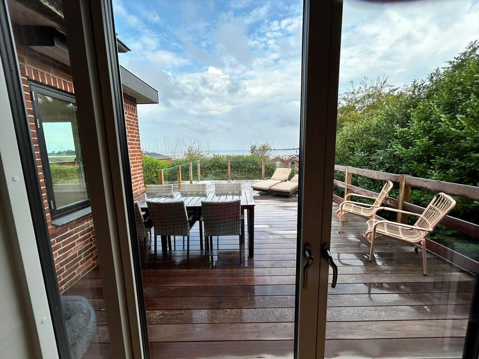 Deck with table, chairs, and loungers. View of sea and boats.