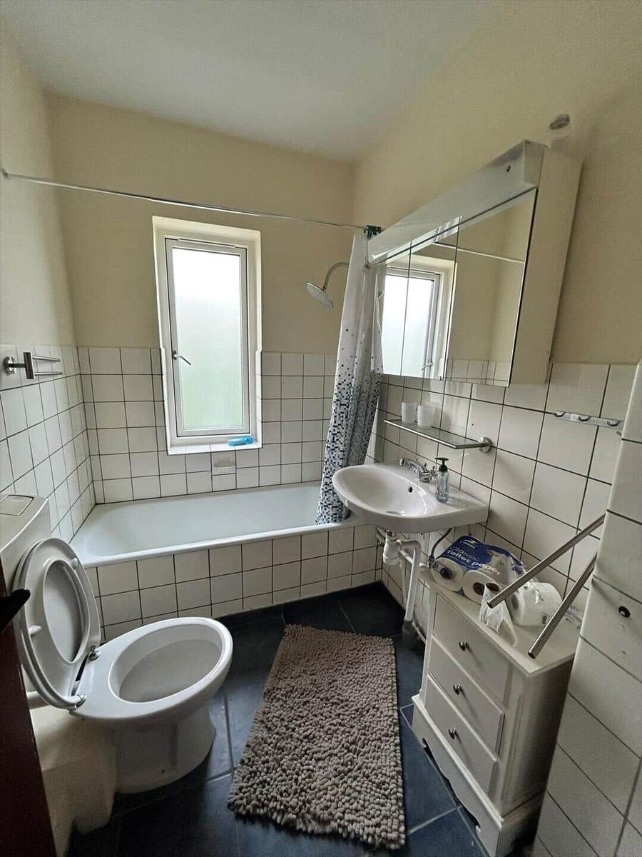 Bathroom with bathtub, showerhead, sink, and mirrored cabinet.
