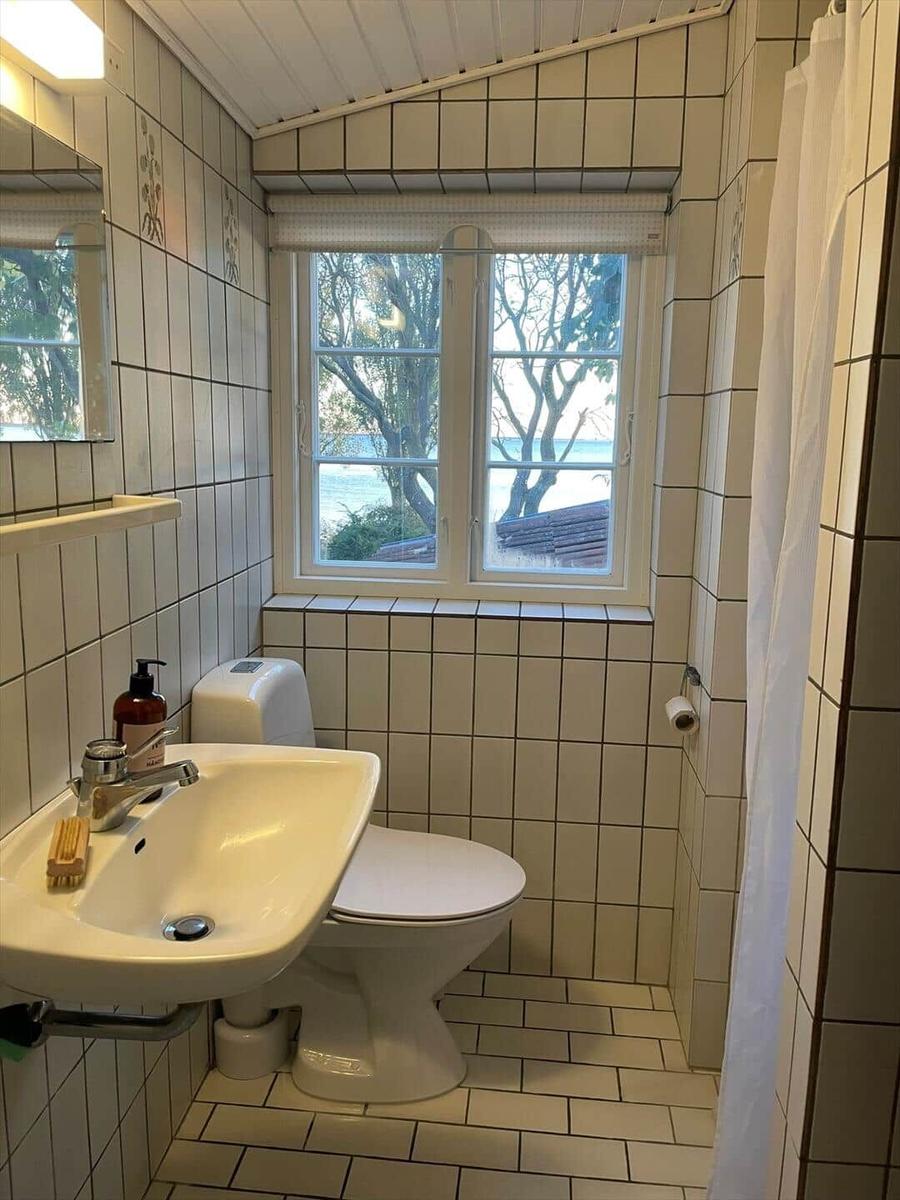 Bathroom with toilet, sink, and window with sea view.