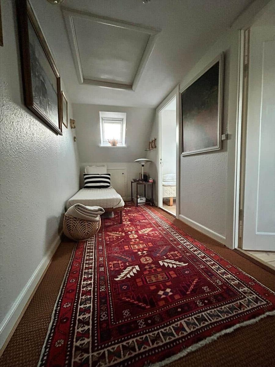 Bedroom with bed, rug, and wall art. Window and door are visible.