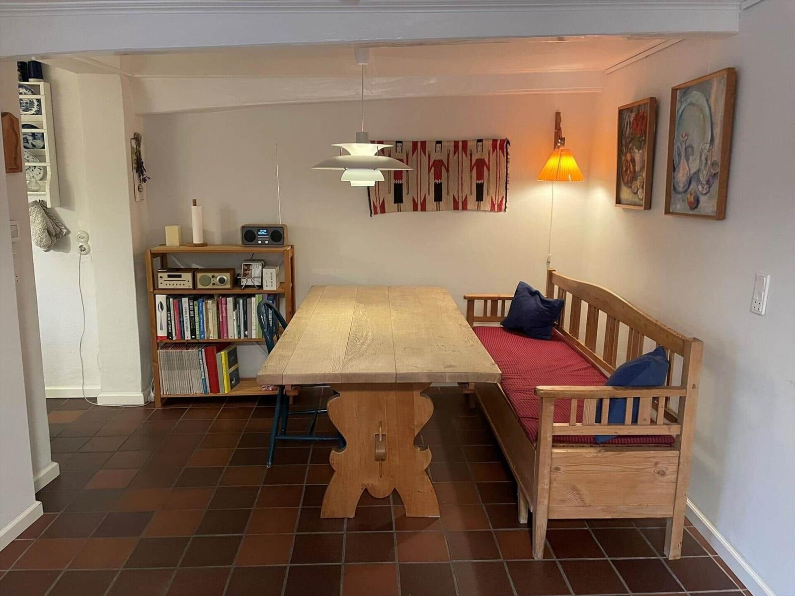 Dining room with wooden table, bench, and bookshelf against the wall.