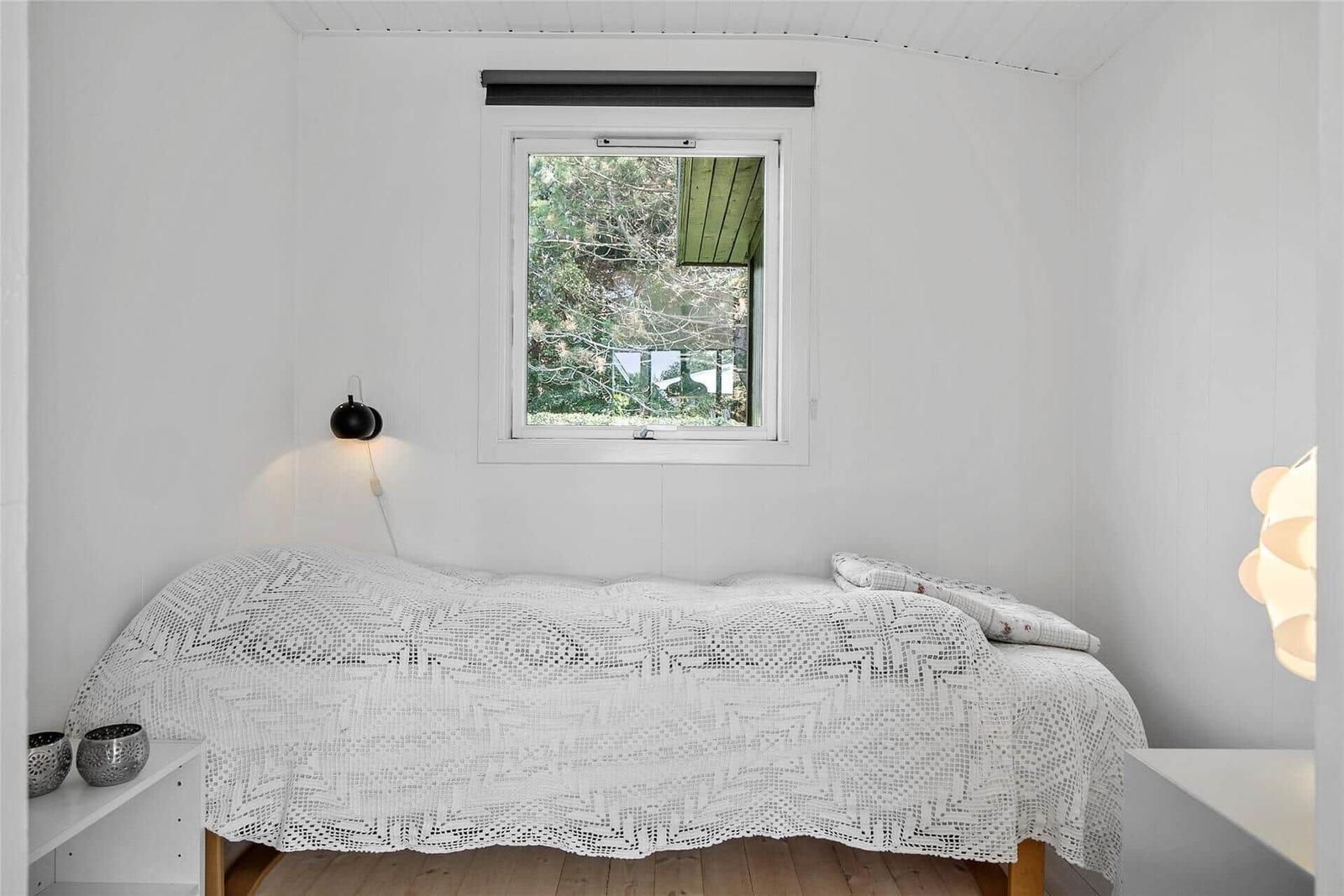 Schlafzimmer mit Bett, Fenster und Lampen.