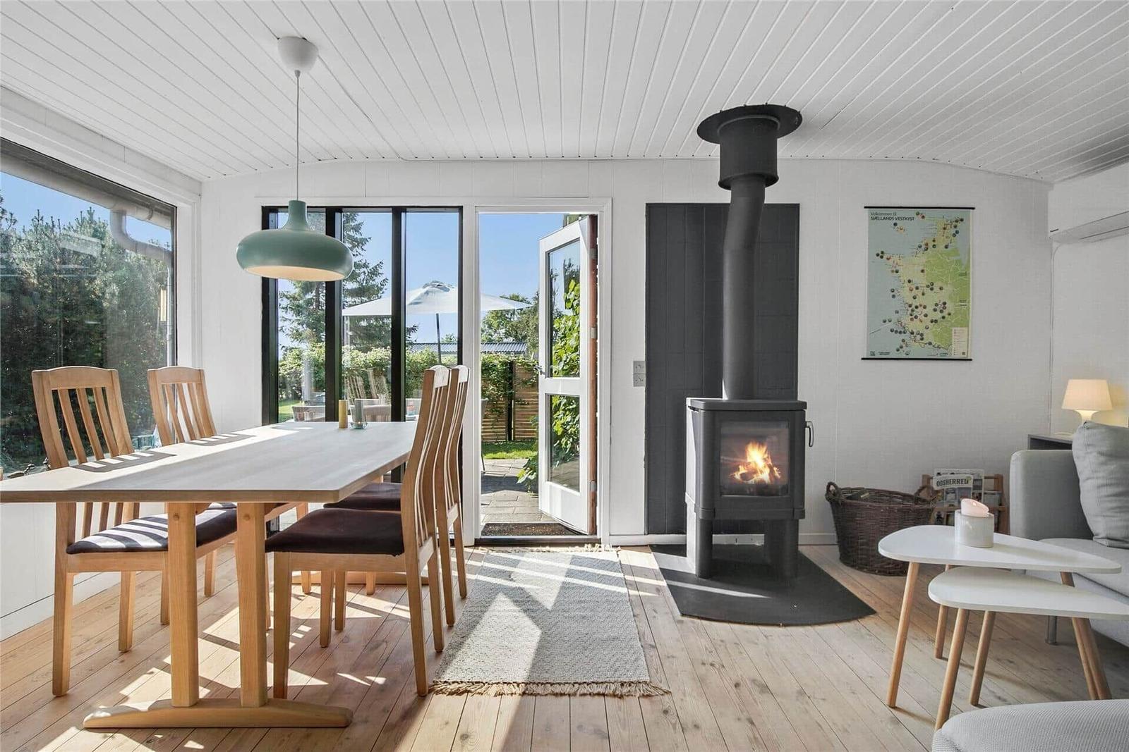 Essbereich mit Tisch und Stühlen, Kamin und Blick auf den Garten.