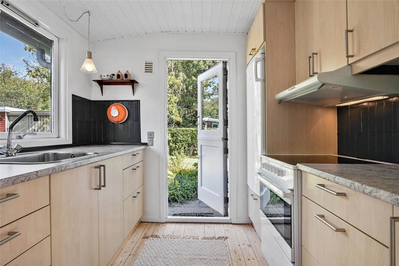 Küche mit Holzmöbeln, Arbeitsfläche und Tür zum Garten.