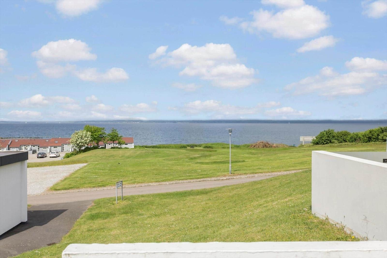 Weitläufiger Grünstreifen mit Blick auf das Meer und einige Häuser im Hintergrund.