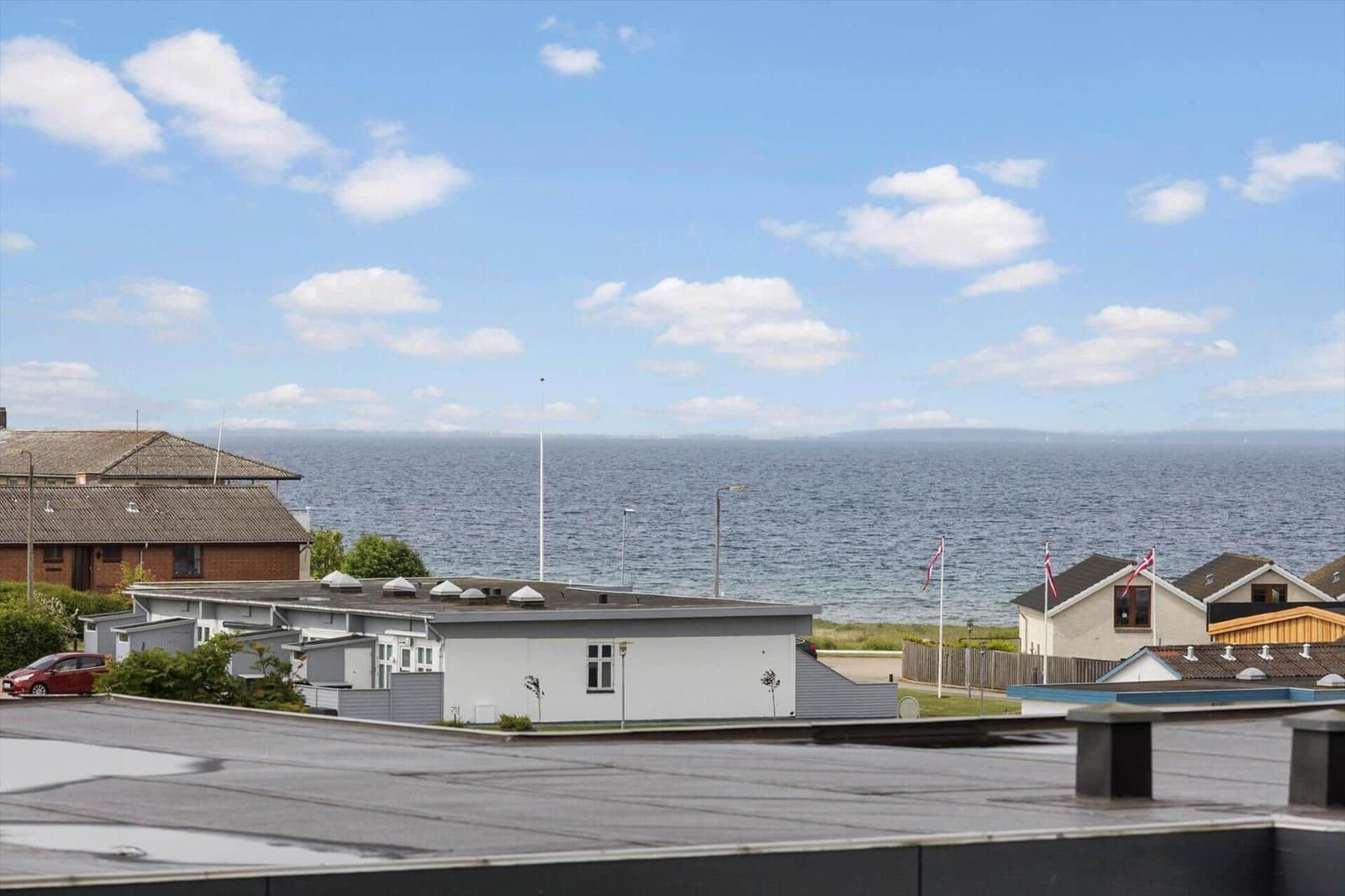 Meerblick mit Häusern und blauem Himmel mit weißen Wolken.