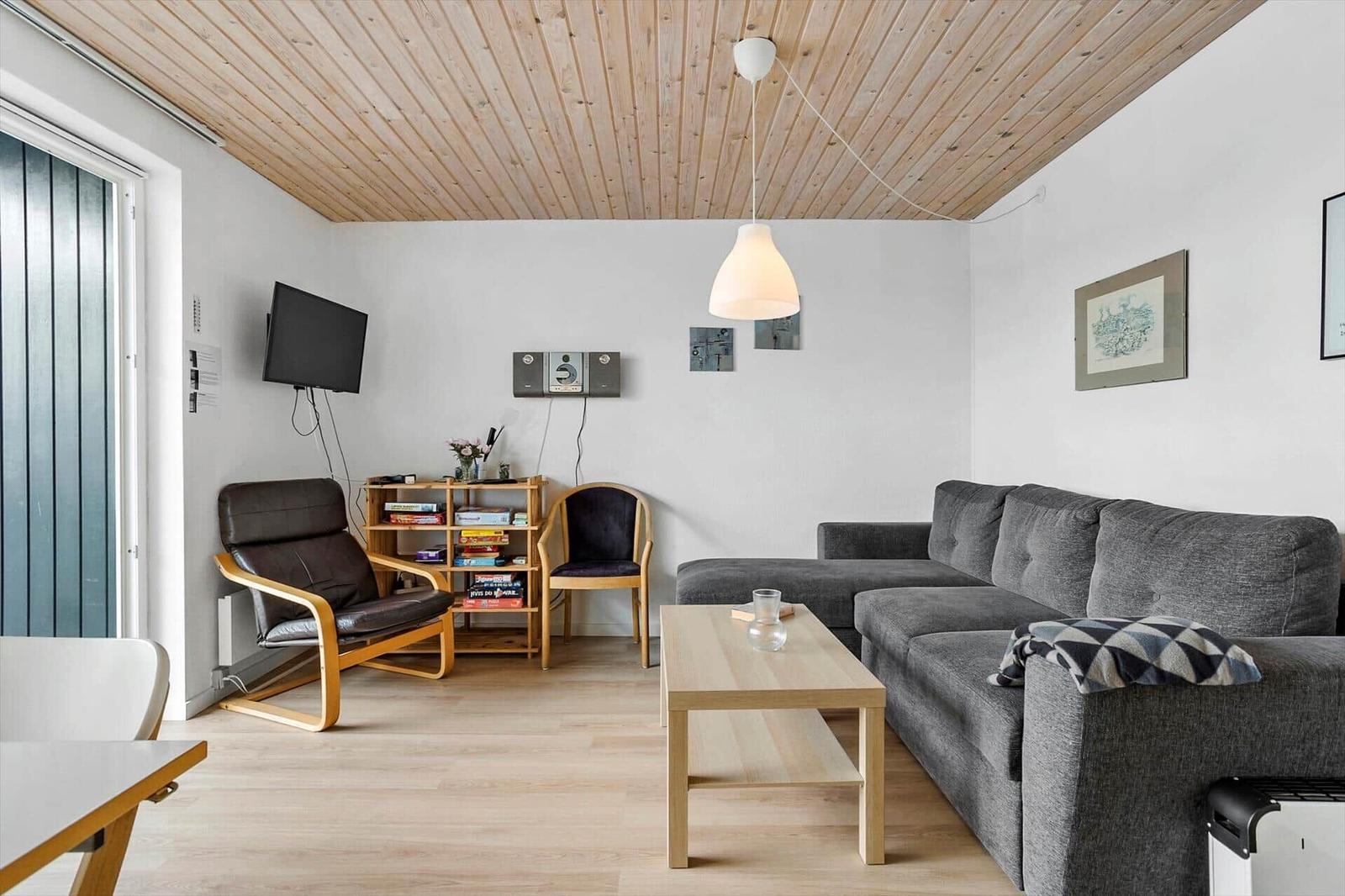 Wohnzimmer mit Sofa, Couchtisch und Fernseher an der Wand.