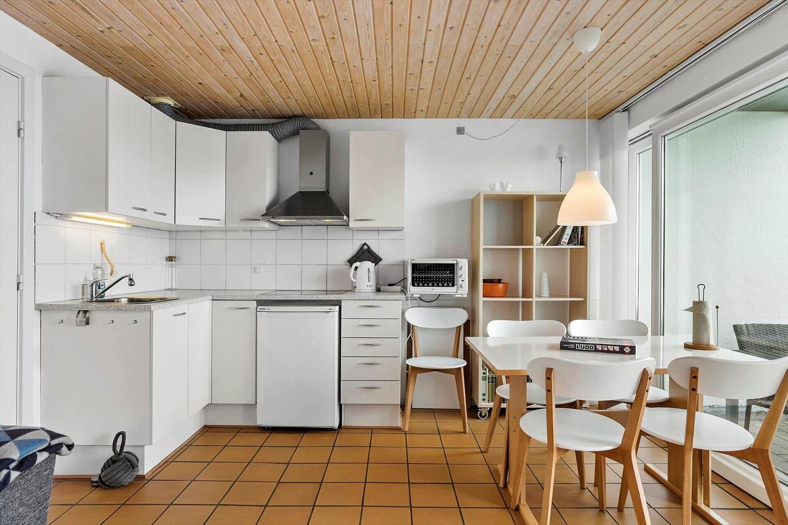Küche mit Essbereich, Holzdecke und Terrassentür.