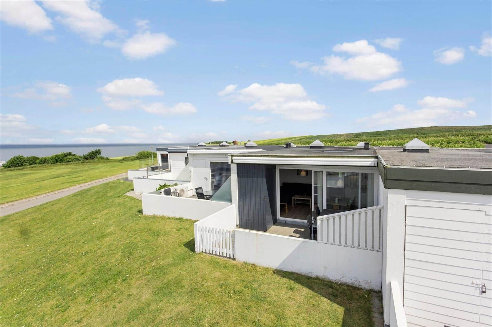 Moderne Ferienwohnung mit Terrasse und Meerblick. Grünfläche und klare Sicht auf das Wasser.