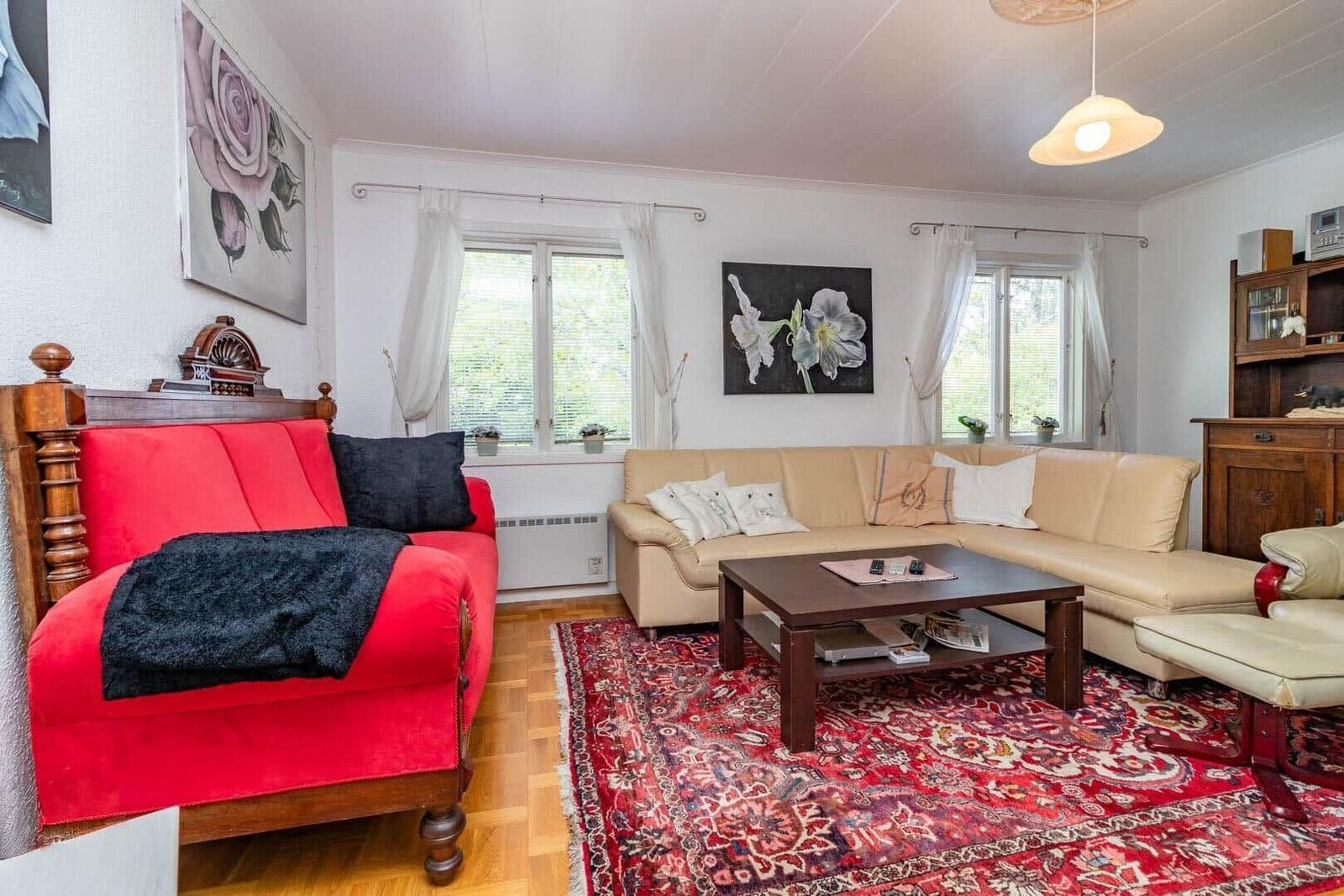 Wohnzimmer mit rotem Sofa, beigem Sofa und orientalischem Teppich.