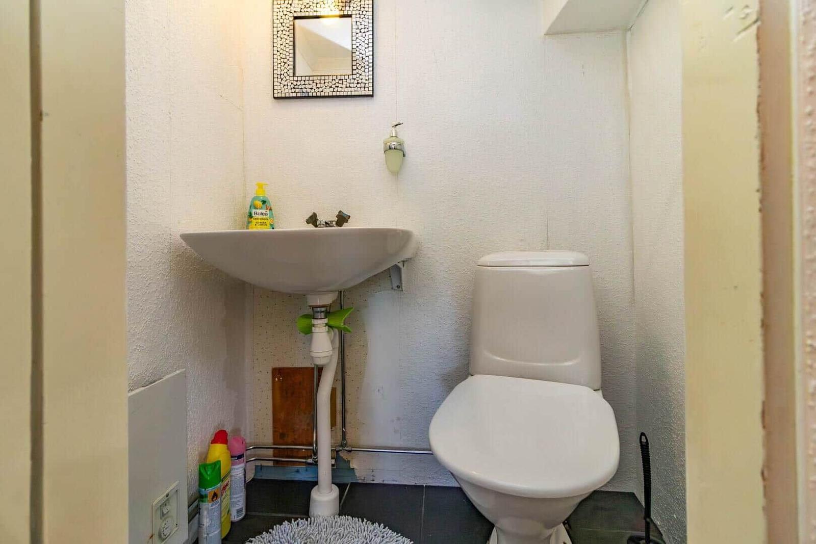 Badezimmer mit Waschbecken, Toilette und Spiegel an der Wand.