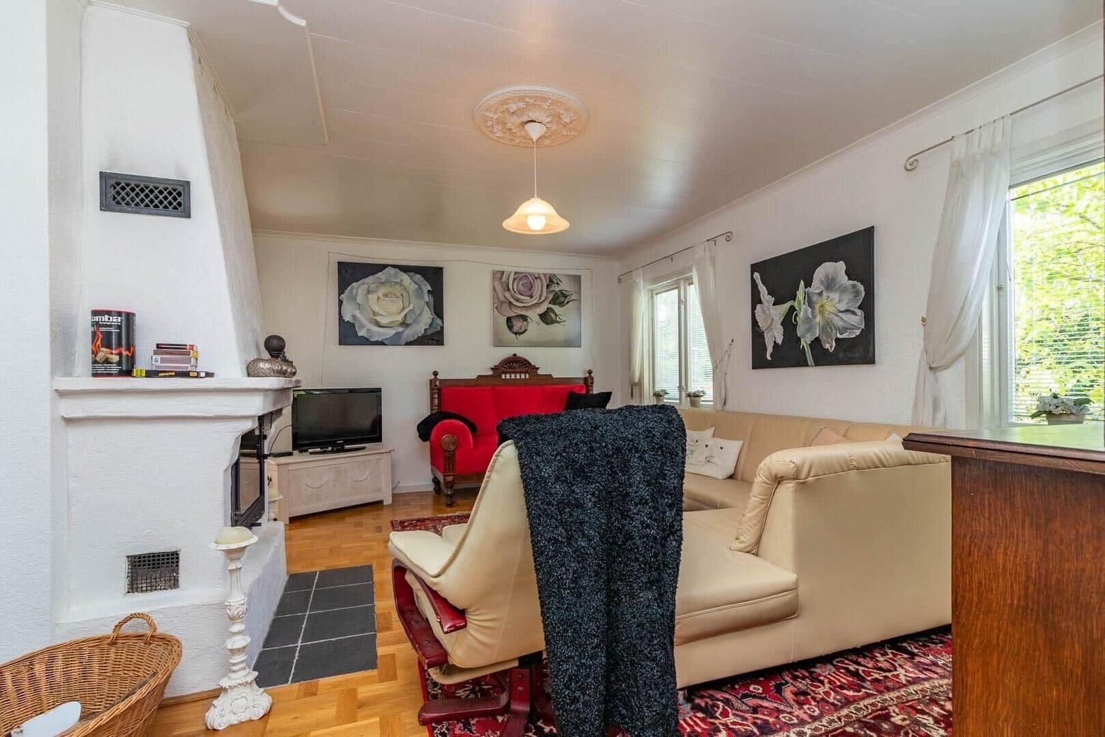 Wohnzimmer mit Sofa, Sessel, Kamin und Wandbildern