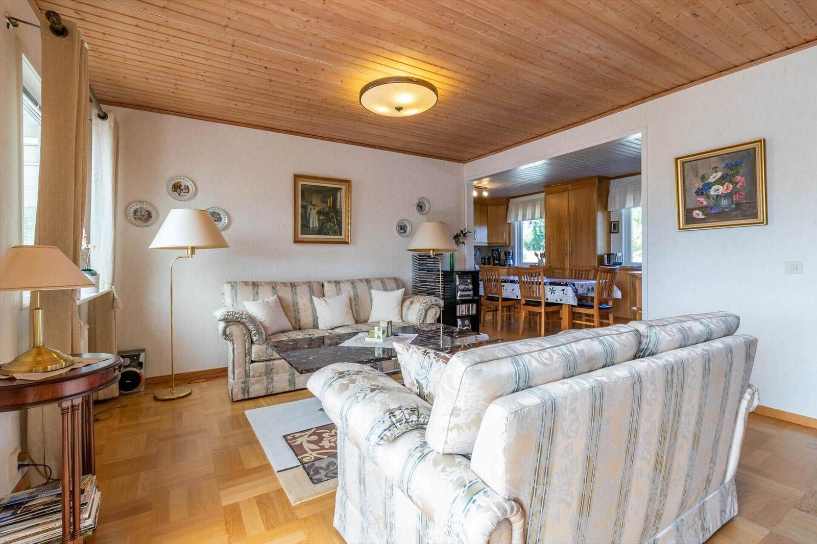 Wohn- und Essbereich mit zwei Sofas, Holzdecke und Tisch mit Stühlen.