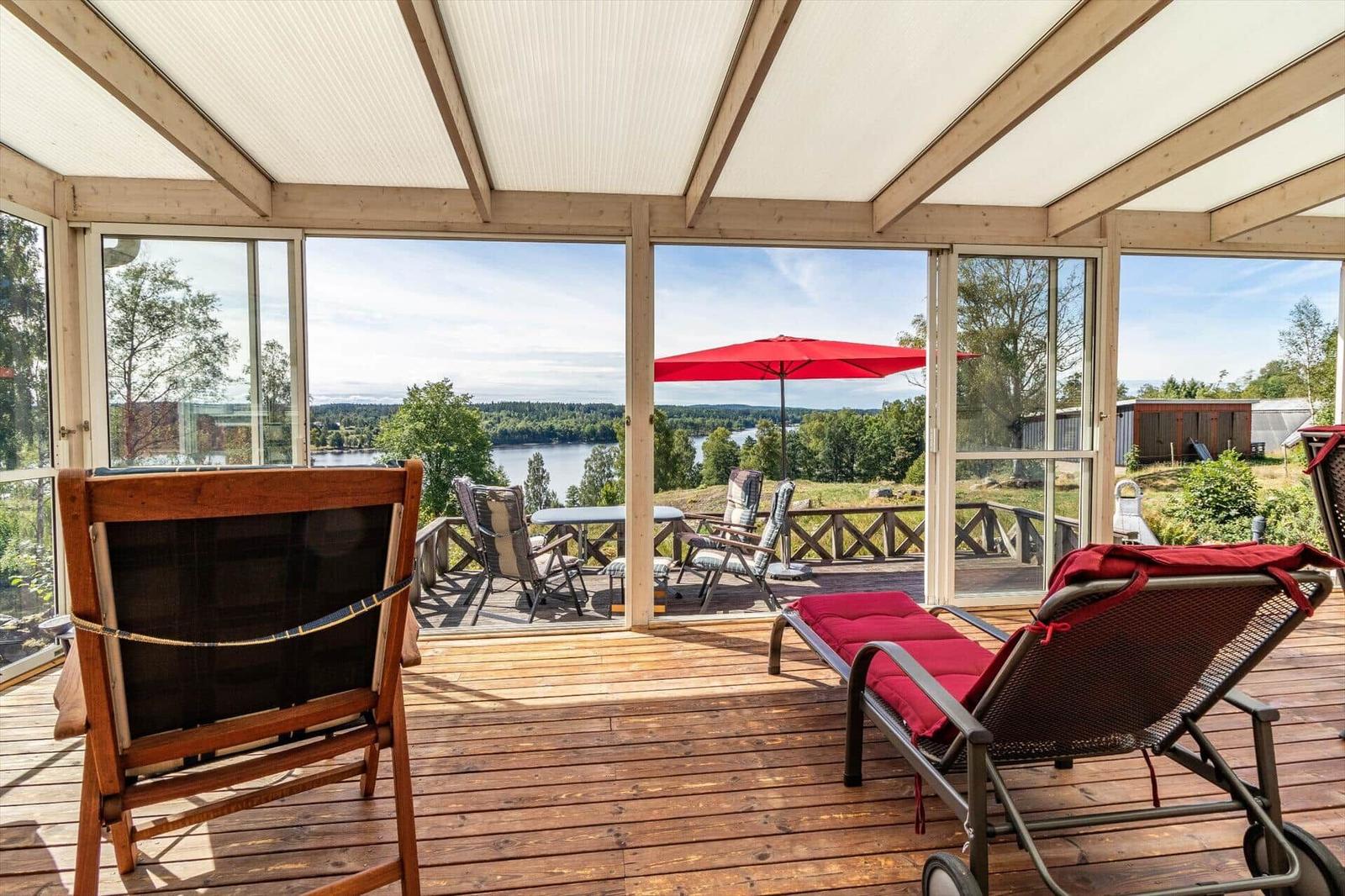 Terrasse mit Blick auf See, rote Liege und Sonnenschutz