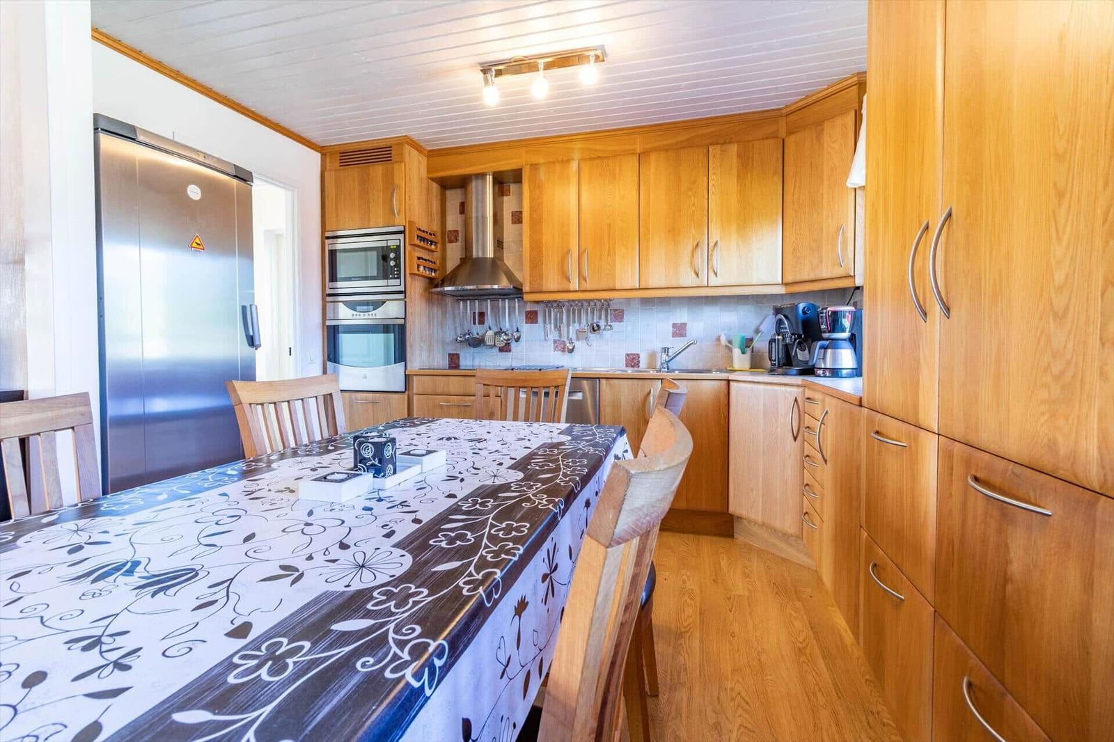 Küche mit Holzmöbeln, Esstisch und moderner Kücheneinrichtung.