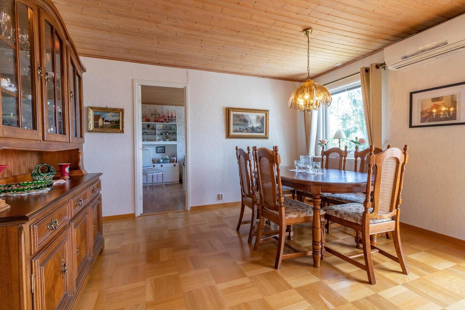 Esszimmer mit Holztisch, Stühlen und Sideboard. Holzdecke und Parkettboden.