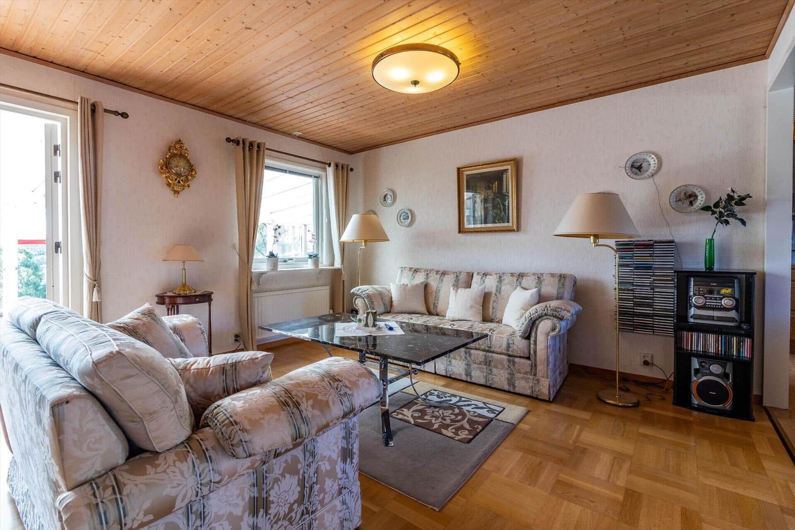 Wohnzimmer mit Holzdecke, Sofa, Couchtisch und Stereoanlage.