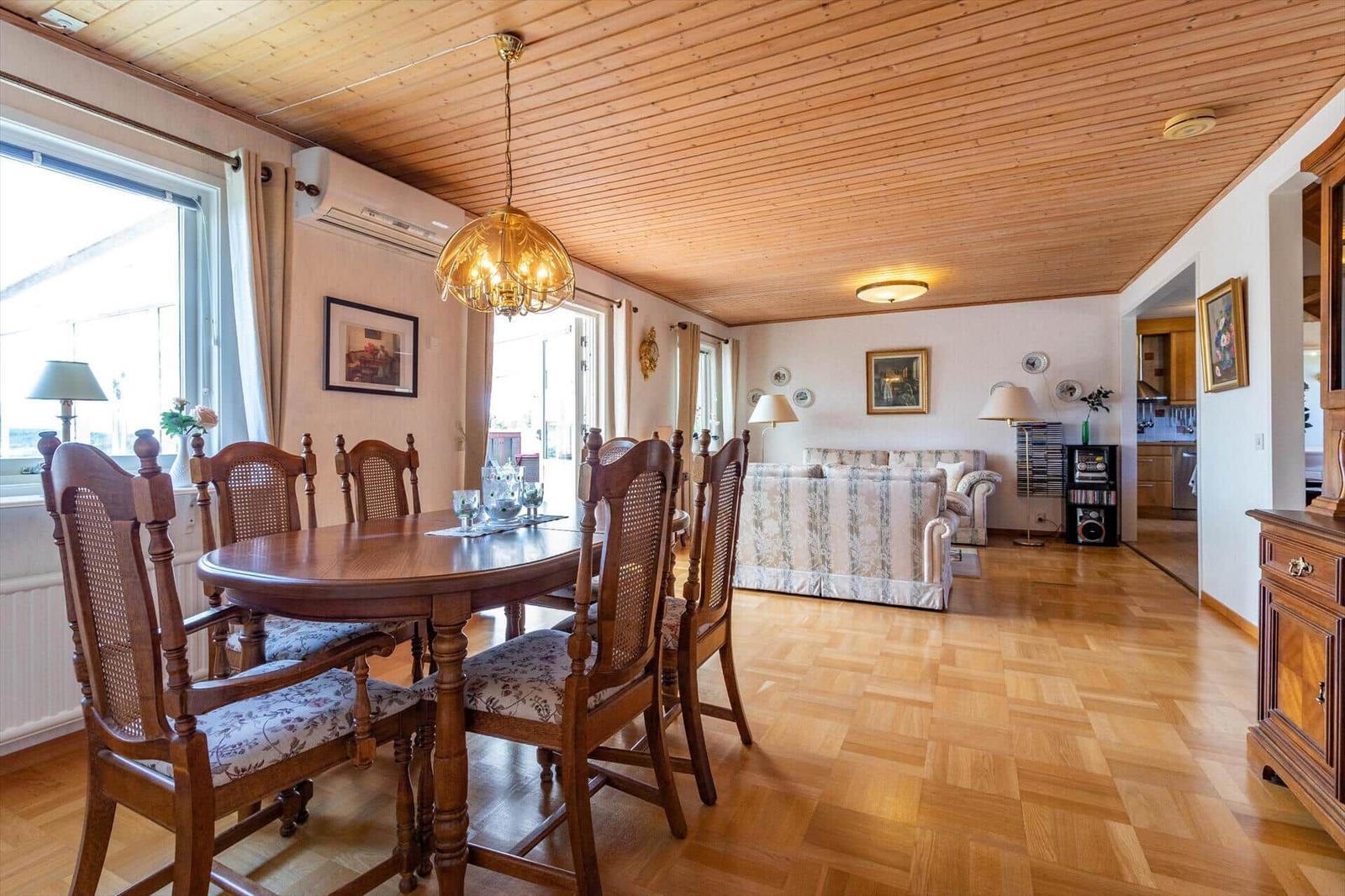 Esszimmer mit Holztisch und Stühlen. Wohnbereich mit Sofa und Holzboden.