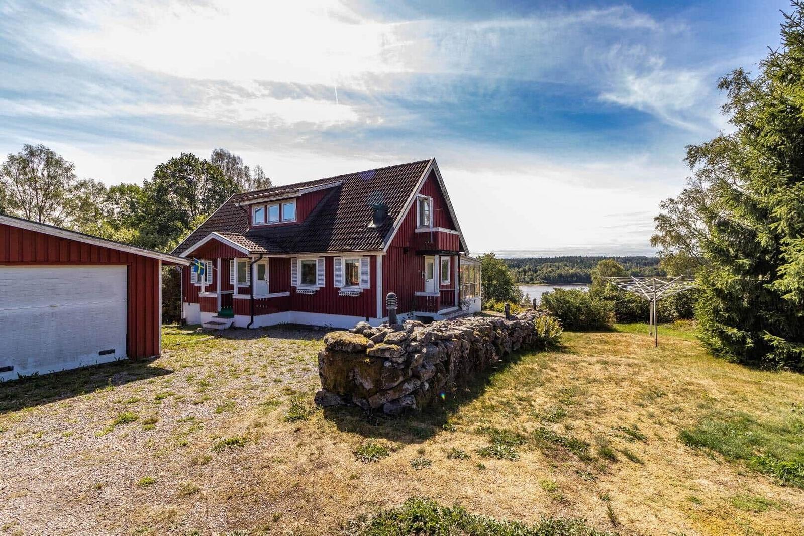 Rotes Holzhaus mit Garage und Blick auf einen See.
