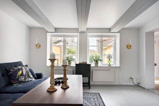 Wohnzimmer mit Sofa, Tisch, Fenstern und Balken an der Decke.