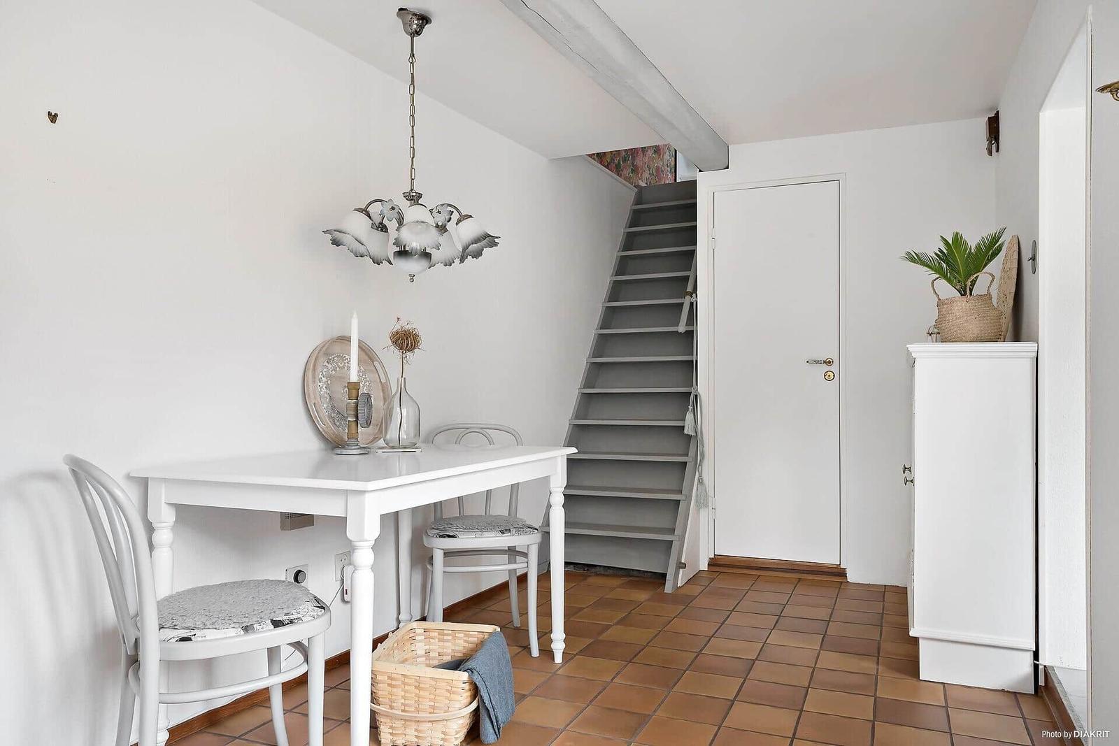 Essbereich mit Tisch, Stühlen und Steintreppe zur oberen Etage.