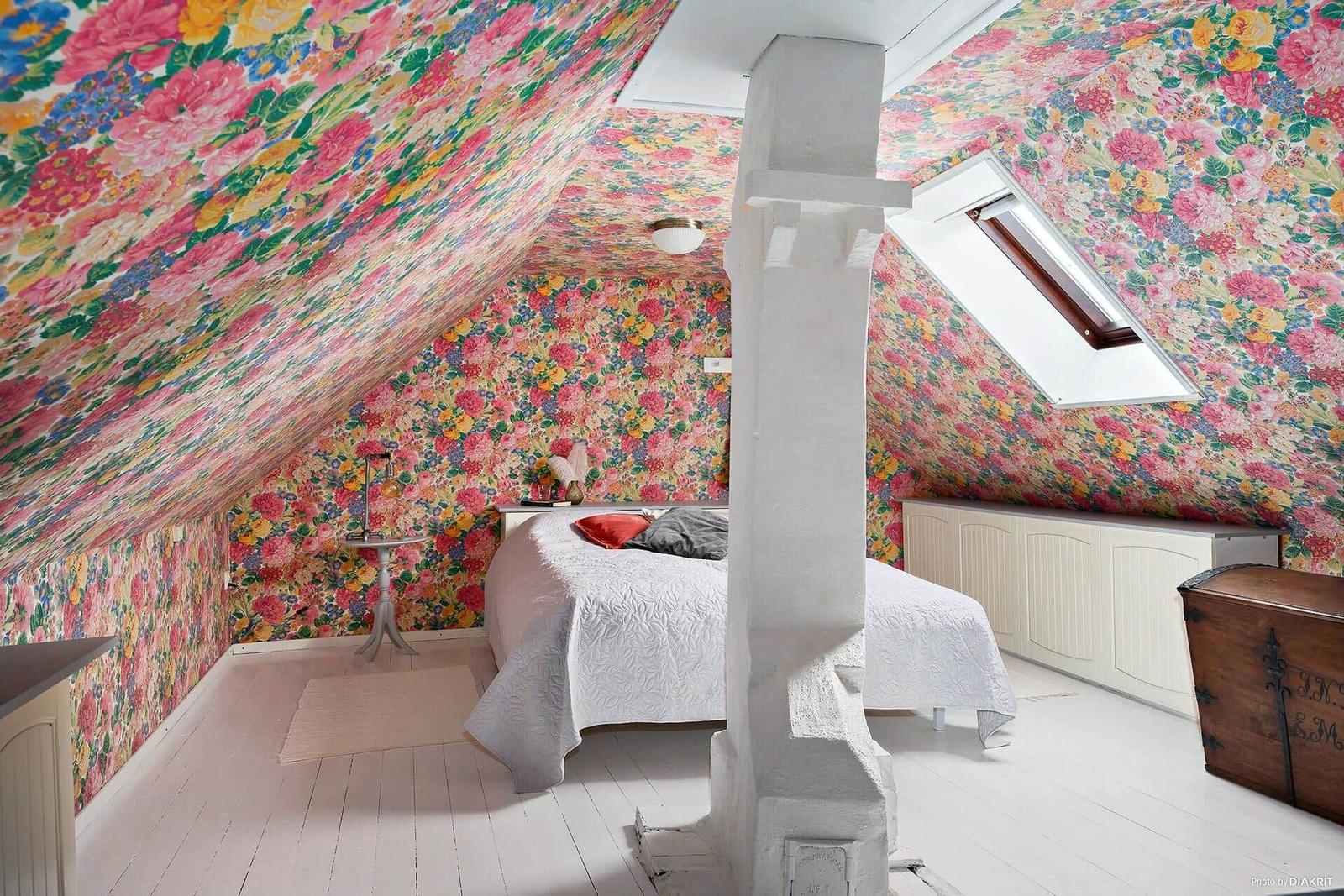 Schlafzimmer mit floraler Tapete, Dachfenster und weißem Boden.