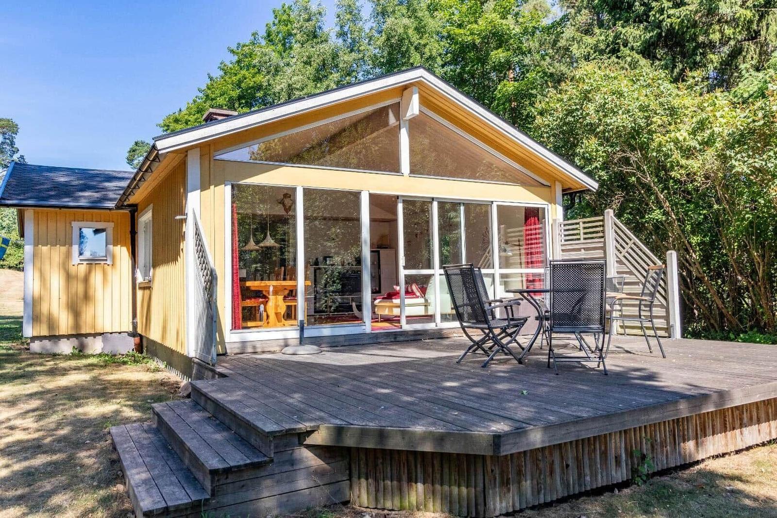 Ein gelbes Haus mit Terrasse und Sitzgelegenheiten im Grünen.