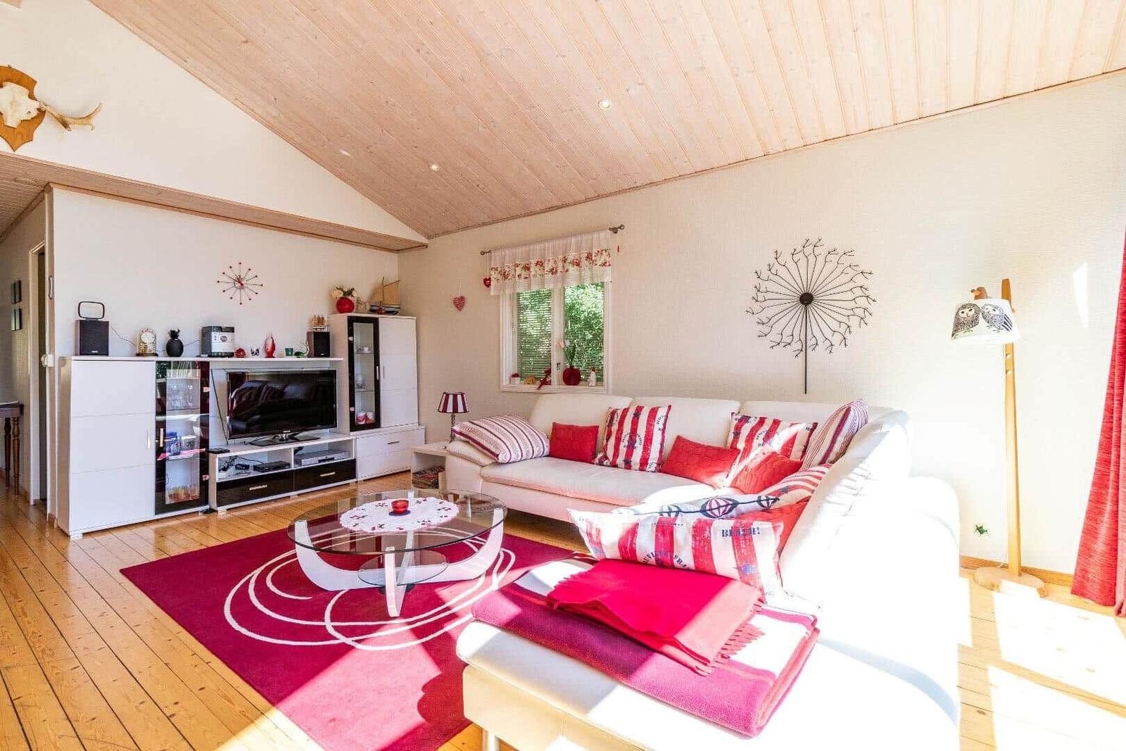 Wohnzimmer mit weißem Sofa, rotem Teppich und Holzdecke.