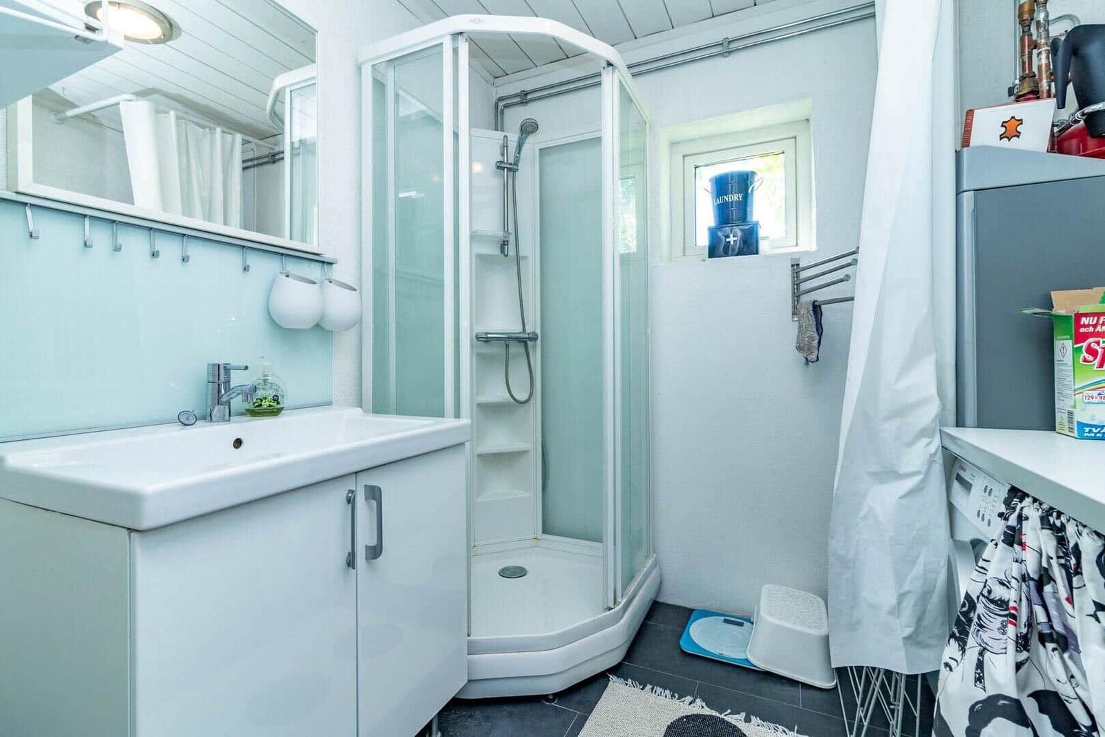 Badezimmer mit Dusche, Waschbecken und Fenster